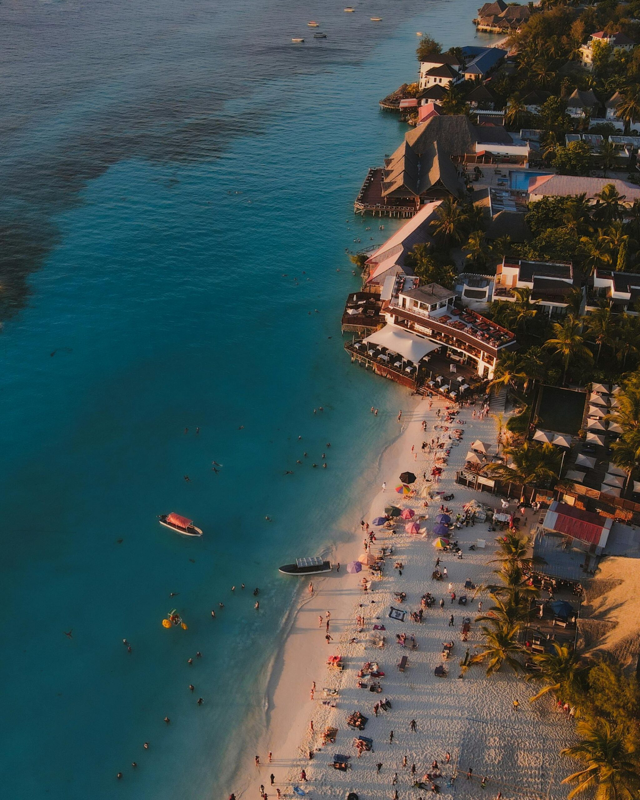 Stunning aerial shot of Nungwi Beach in Tanzania with people enjoying the shore at sunset.