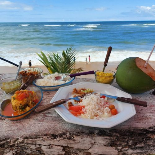 Tropical meal with rice and curry, served by the beach with coconut water and ocean view.